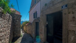 A narrow street with a stone wall on one side and a building with a sign indicating room number 11.