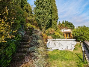 A garden with a stone staircase, a covered outdoor table, and a building with a yellow facade. - Beaming Holiday Home in Marciaga With Pool, Garden,terrace (Costermano sul Garda)