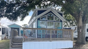 A two-story mobile home with a porch and a fenced deck area. - Cozy park model at campground in enchanting Newport NC. (Newport)
