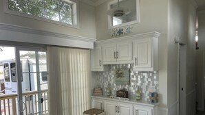 A kitchen with white cabinets, a marble countertop, and a view of a deck. - Cozy park model at campground in enchanting Newport NC. (Newport)