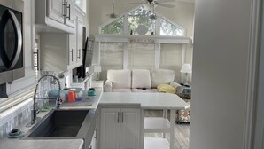 A modern kitchen with white cabinetry, a built-in oven, and a dining area with a white table and bench. - Cozy park model at campground in enchanting Newport NC. (Newport)