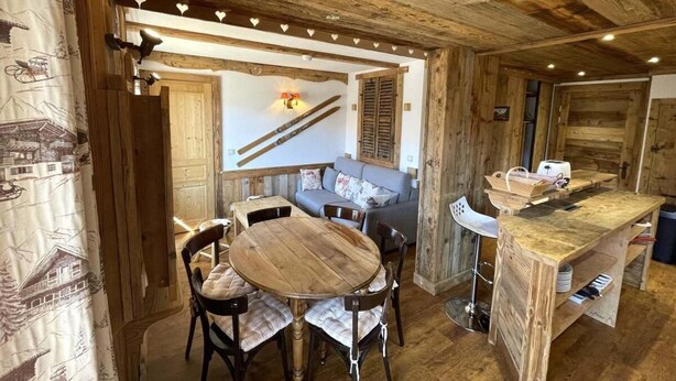 A rustic wooden interior with a round wooden table and chairs, a sofa, and a kitchen area with a wooden countertop. - 100m from shops, Ground floor, view mountain, balcony, tv, 53m², Les Menuires (Les Menuires)