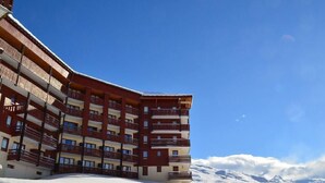 A multi-story hotel with balconies, set against a snowy mountain backdrop. - 100m from shops, Ground floor, view mountain, balcony, tv, 53m², Les Menuires (Les Menuires)