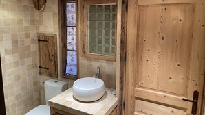 A bathroom with a wooden door, a toilet, a sink, and a window with a frosted glass pane. - 100m from shops, Ground floor, view mountain, balcony, tv, 53m², Les Menuires (Les Menuires)