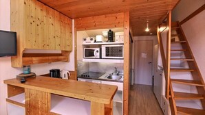 Una cocina compacta con armarios de madera, microondas, estufa y pileta.