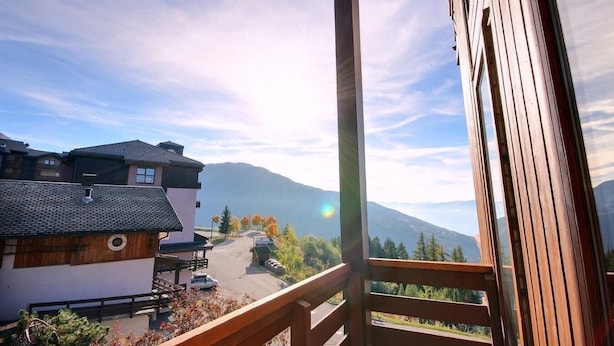 Un balcón con vista a una cadena montañosa y una carretera con coches.