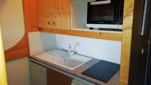 A compact kitchen with a built-in microwave, a sink with a drying rack, and wooden cabinets. - 50m from resort center, 14th floor, balcony, tv, 29m², Les Arcs (Les Arcs)