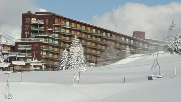 A multi-story hotel with balconies, a ski slope, and snow-covered trees. - 50m from resort center, 14th floor, balcony, tv, 29m², Les Arcs (Les Arcs)