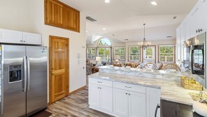 Una cocina amplia con una isla grande, electrodomésticos de acero inoxidable y muebles de madera.