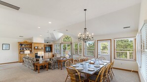 Amplia sala de estar con comedor, chimenea y ventanas grandes.