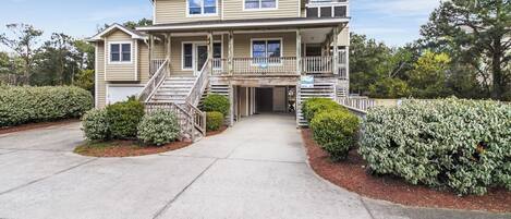 A two-story building with a front porch, a staircase, and a sign indicating the address.