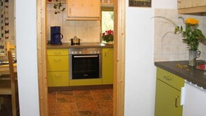 A kitchen with yellow cabinets, a coffee maker, a stove, and a milk sign on the wall. - Mrs. Monika Rasehorn (Altenberg)