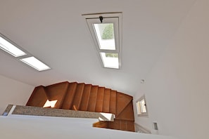 A modern interior with a sloped ceiling, skylights, and a built-in fireplace. - Nice Apartment with Pool (Siracusa)