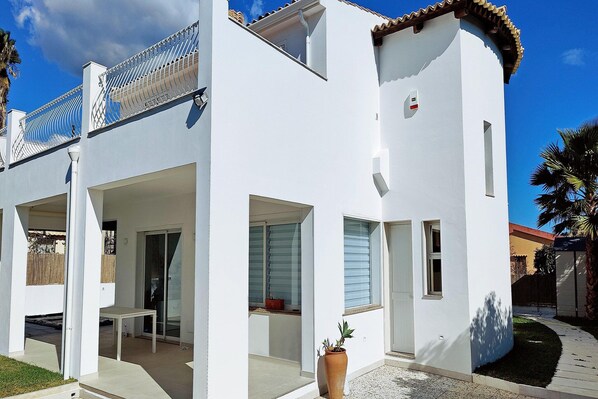 A white building with a balcony, a door, and a potted plant. - Nice Apartment with Pool (Siracusa)