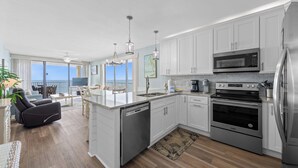 A modern kitchen with white cabinets, stainless steel appliances, a dishwasher, and a large island with a sink. - 🌊 Romar Place 1106 | Top Floor Gulf Front | Corner Balcony + Resort Amenities (Orange Beach)