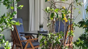 Un patio con una mesa y sillas, una planta en maceta y un limonero.