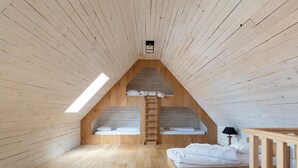 A high-ceilinged room with wooden walls and floors, a skylight, a loft bed, a ladder, and a bedside table with a lamp. - Modern Home by the Sea (Nieuwpoort)
