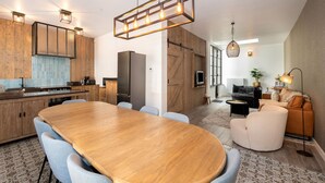 A modern kitchen with a wooden dining table, light blue chairs, and a built-in oven. - Modern Home by the Sea (Nieuwpoort)