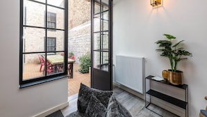 A modern room with large windows, a black-framed door, a radiator, a plant, and a small console table. - Modern Home by the Sea (Nieuwpoort)