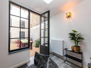 Relax in a cozy seating area with a sofa and side table, overlooking a charming courtyard.