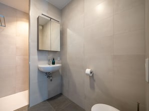 A modern bathroom with a sink, mirror, and toilet.