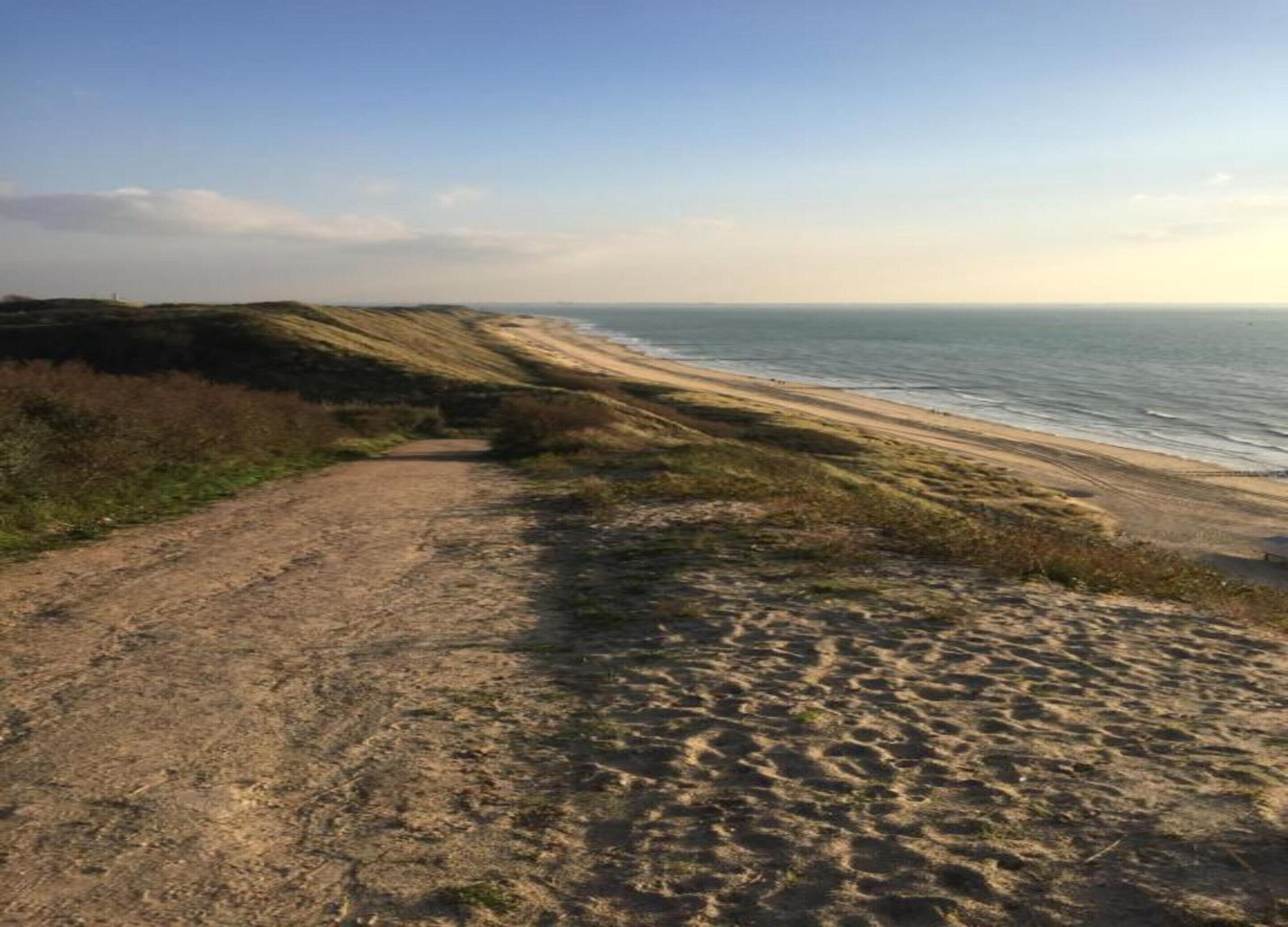 En kyststi der fører til en strand med frit udsyn over havet.