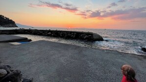 A sunset view from a pier with a rocky shoreline and a clear sky. - 3 Bedroom Apartment in Massa Lubrense (Massa Lubrense)