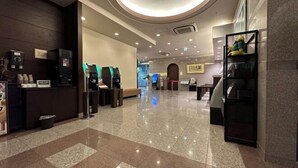 A hotel lobby with a reception desk, self-service kiosks, a staircase, and a wall-mounted shelf with a stuffed toy. - Hotel Route-Inn Hakata Ekimae -Hakataguchi- (Fukuoka)