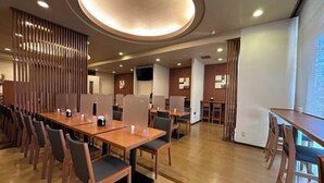 A modern dining area with wooden tables and chairs, recessed ceiling lighting, and a view of the outdoors. - Hotel Route-Inn Hakata Ekimae -Hakataguchi- (Fukuoka)