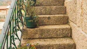 Una escalera de piedra con plantas en macetas, barandilla de metal y una mesa con sillas en la parte superior.