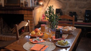 A wooden dining table with a fruit bowl, a pitcher of orange juice, a glass of water, a vase with greenery, and a plate of grapes. - GerêsTER  (Terras de Bouro)