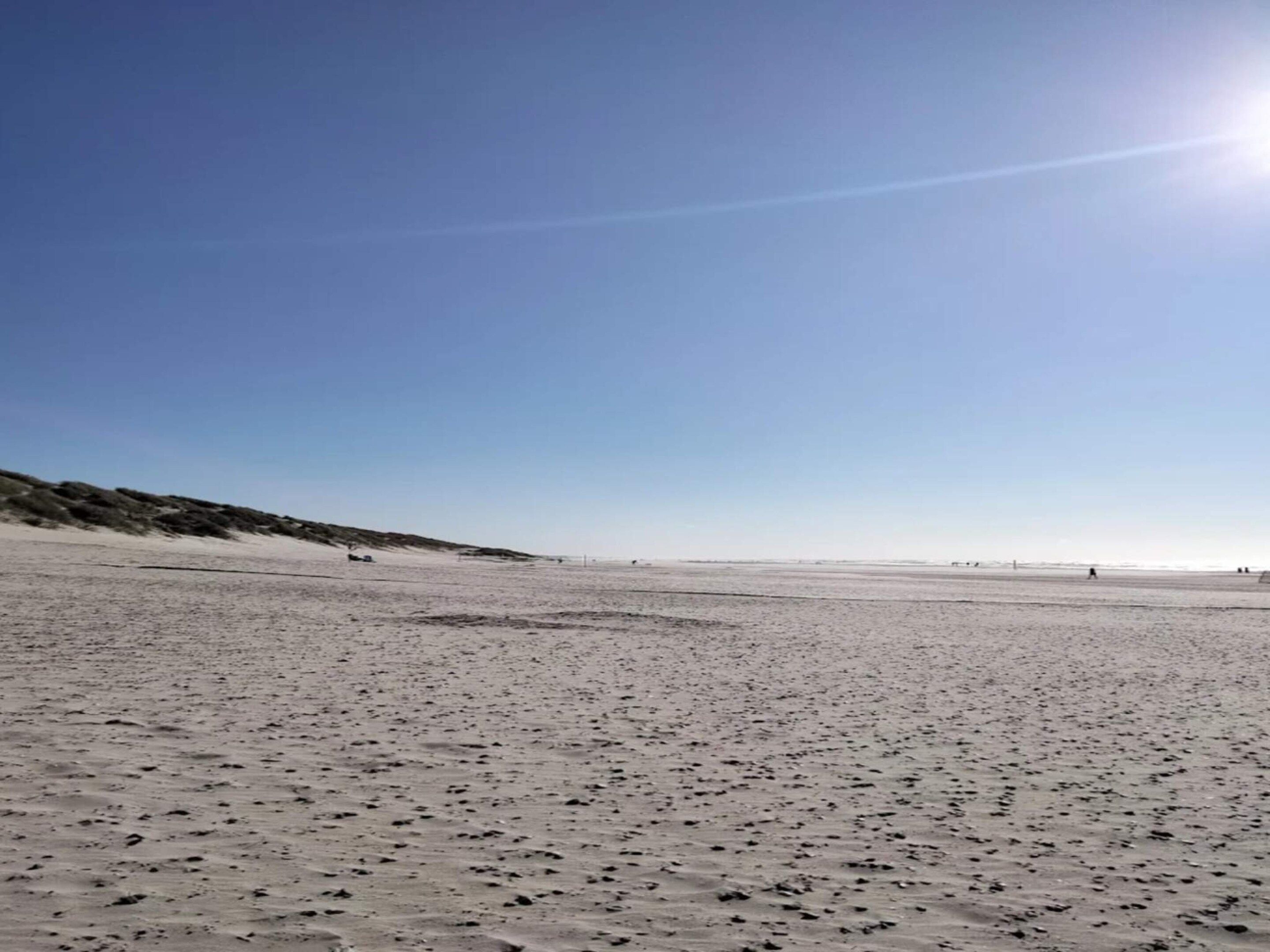 A wide, open sandy beach with a clear sky.