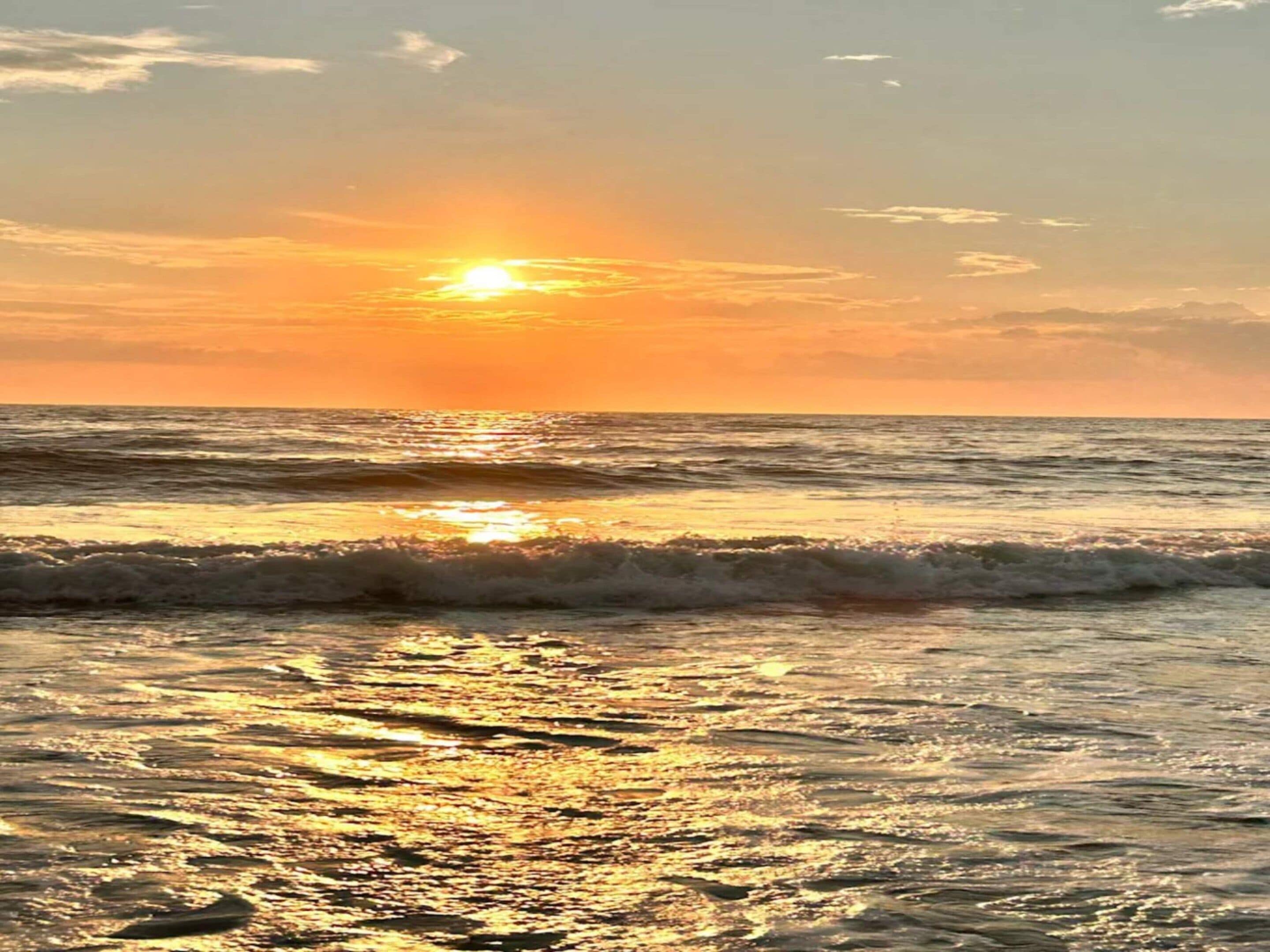 Una puesta de sol sobre el océano, con olas que reflejan la luz del sol.