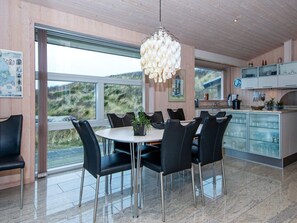 Un espace repas moderne avec une table ronde, des chaises noires et un lustre original.