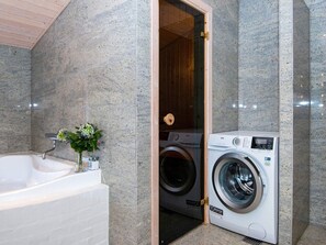 Bathroom features a bathtub, washing machine, and a potted plant.