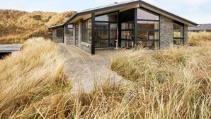 A modern building with large glass windows, a stone facade, and a pathway leading to the entrance. - 5 Star Holiday Home in Henne (Henne)