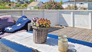 A wooden deck with a white railing, a wicker basket with flowers, a blue blanket, and a white mat. - 6 Person Holiday Home in Skjaerhalden (Hvaler)
