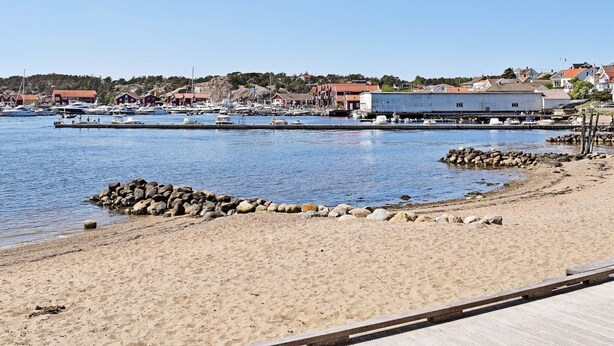 A coastal marina with boats docked, a sandy beach, and buildings in the background. - 6 Person Holiday Home in Skjaerhalden (Hvaler)