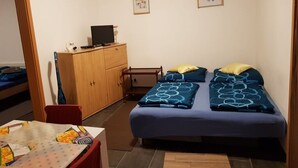 Una habitación pequeña y ordenada con una cama individual, un escritorio y un armario de madera.