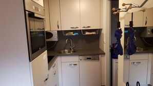 Cocina compacta con microondas, horno, fregadero y lavavajillas.