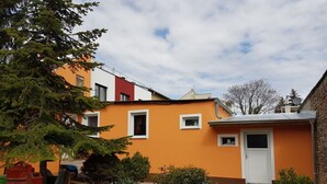 Un edificio residencial con una fachada de color naranja brillante, una puerta blanca y ventanas pequeñas.
