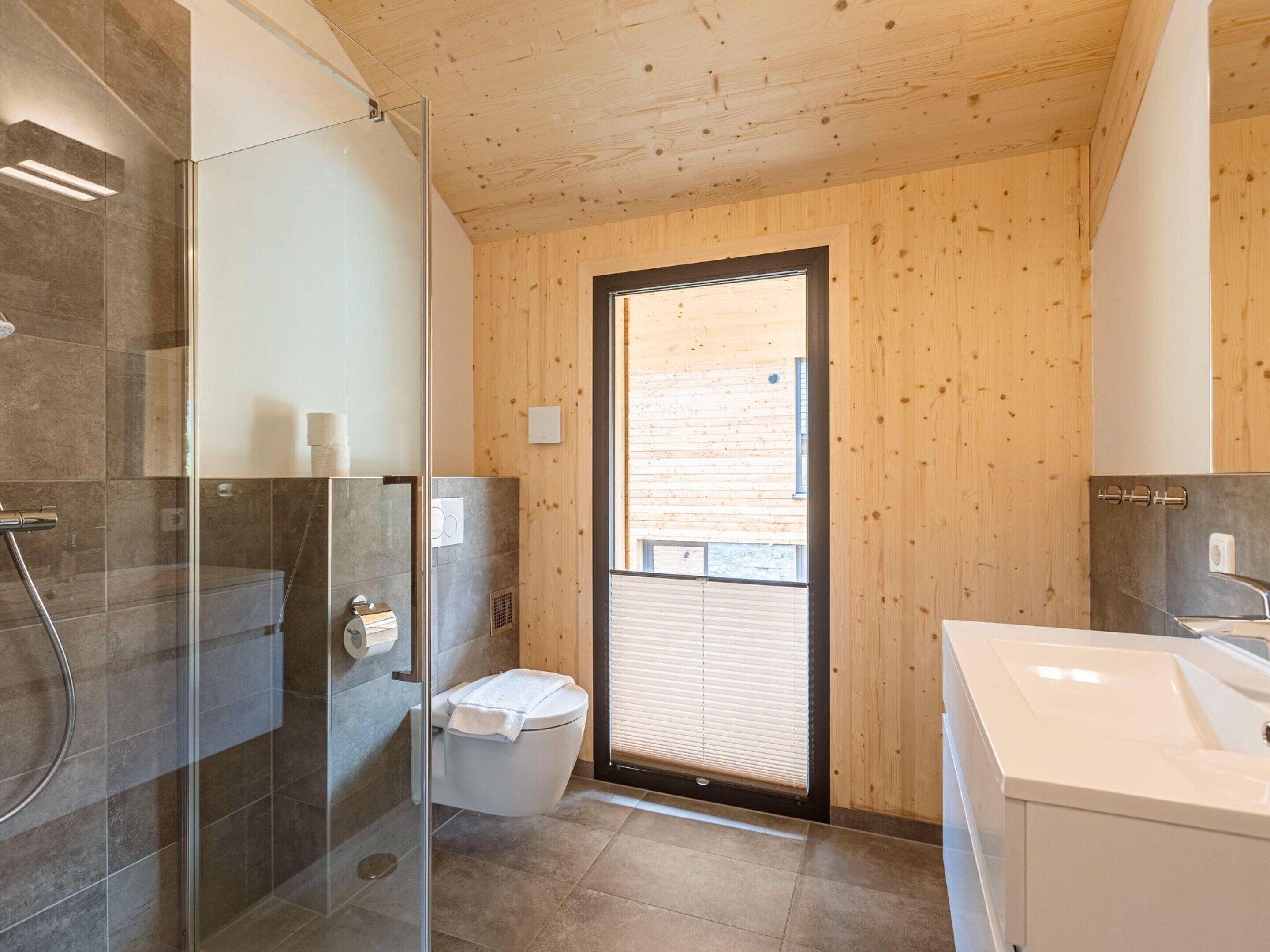 A modern bathroom with a glass shower enclosure, a toilet, and a sink.