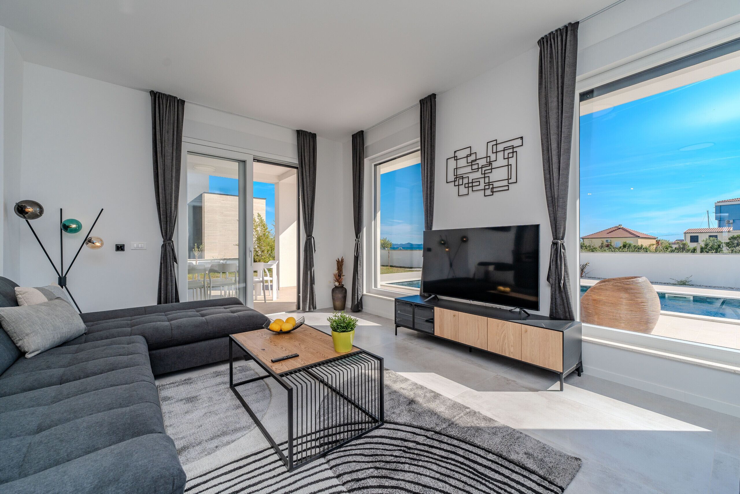 A modern living room with a sectional sofa, a TV, and a dining area.