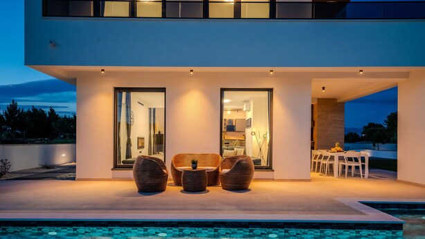 Una casa moderna con piscina, mobiliario exterior y zona de comedor.