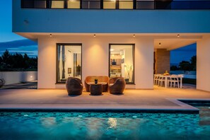 A modern house with a swimming pool, outdoor seating, and a dining area. - Villa Karlo (Privlaka)