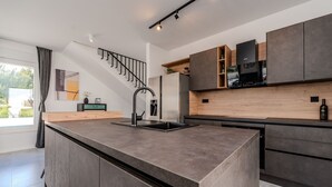 Una cocina moderna con una isla central, armarios oscuros y una campana extractora de acero inoxidable.