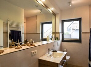 A modern bathroom with a large mirror, a sink, and a window. - Uitzicht op de Kraanvogel (Dreschvitz)