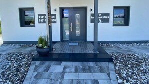 A modern building with a covered entrance, a black door, and two windows with signage. - Uitzicht op de Kraanvogel (Dreschvitz)