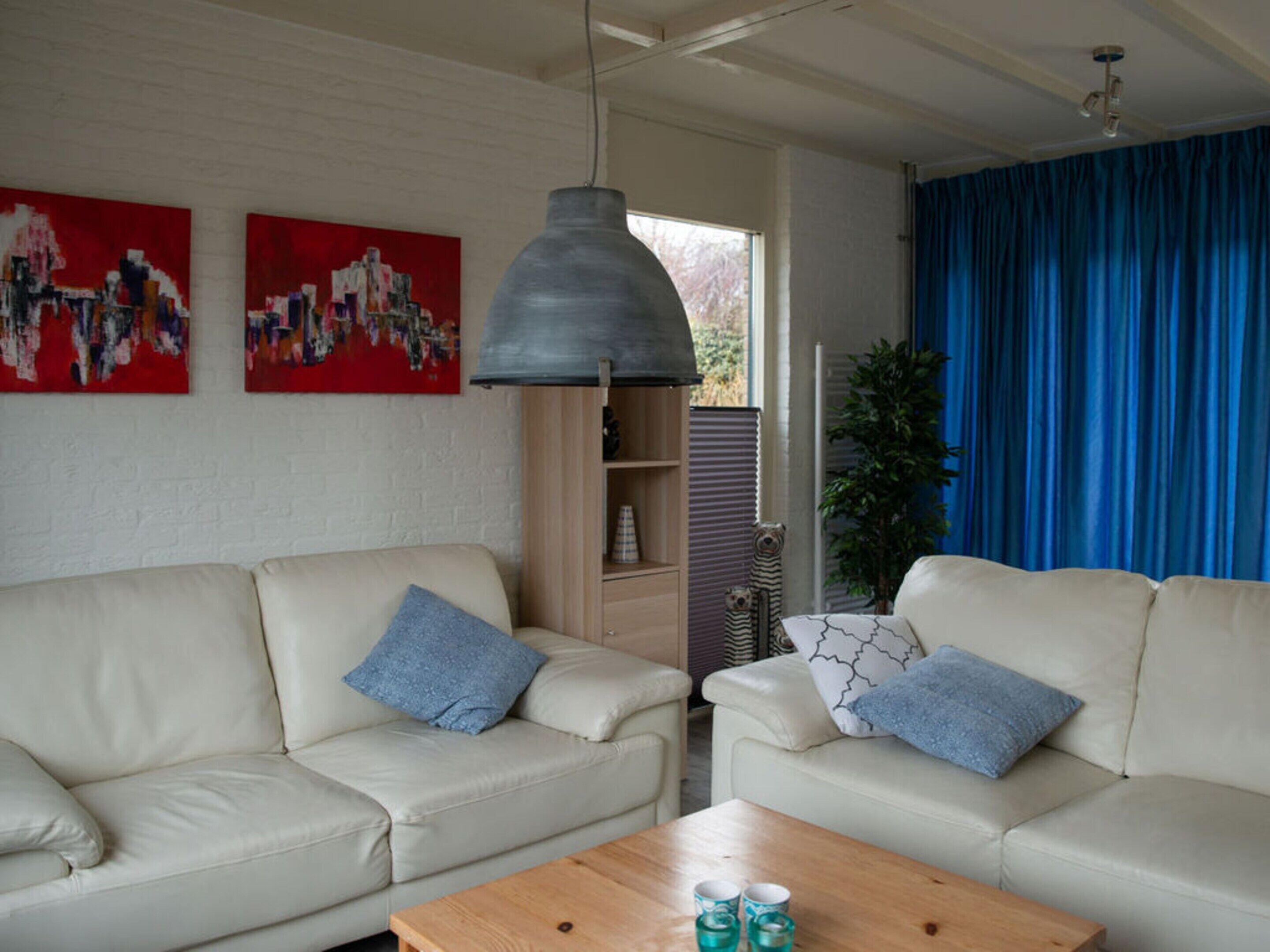 A living room with two beige sofas, a wooden coffee table, and a hanging pendant light.