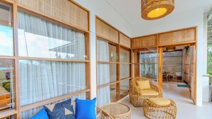 Una habitación con ventanas amplias, muebles de mimbre e iluminación de techo.
